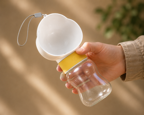 Portable dog water bottle Cuki Flow Mini with cloud-shaped bowl, held indoors with natural light